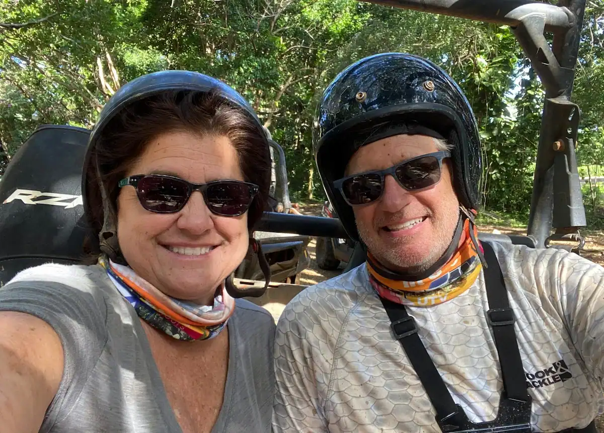 Matt and Linda smiling in helmets before a muddy UTV adventure in Jamaica.