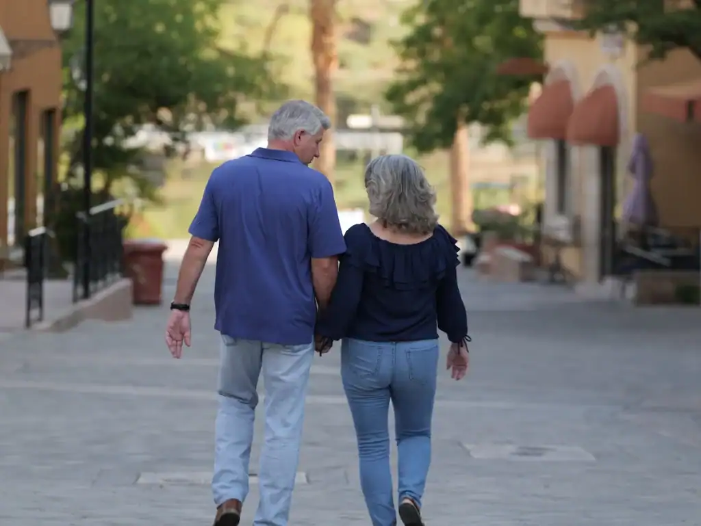 Matt & Linda walking away holding hands on a quiet street.