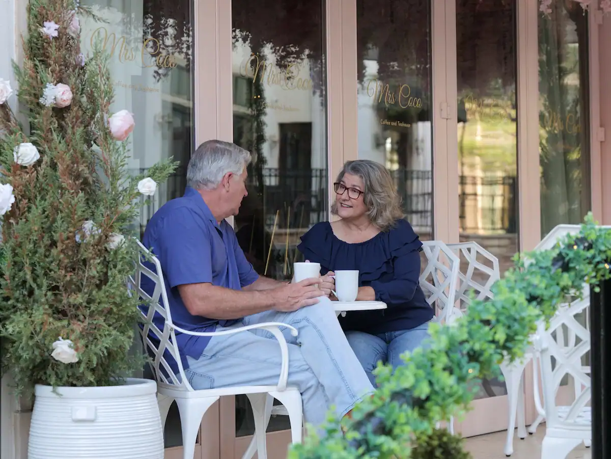 Matt & Linda talking over coffee at an outdoor table before making a big life change.