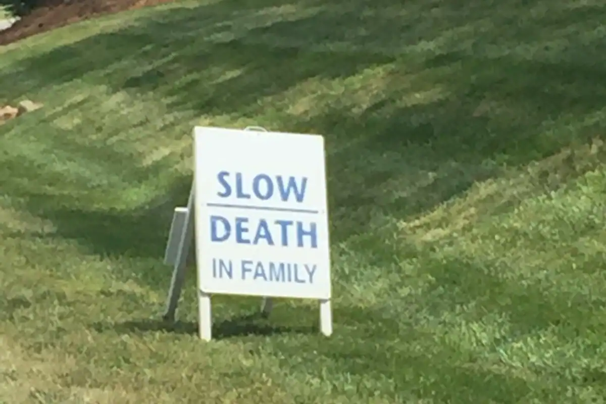 A yard sign that reads “SLOW DEATH IN FAMILY,” symbolizing how living life by default slowly erodes you.