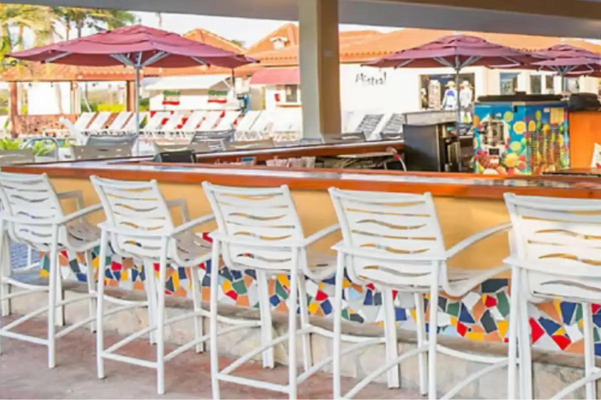 Poolside beach bar with colorful mosaic tile and white stools at La Cabana Resort in Aruba
