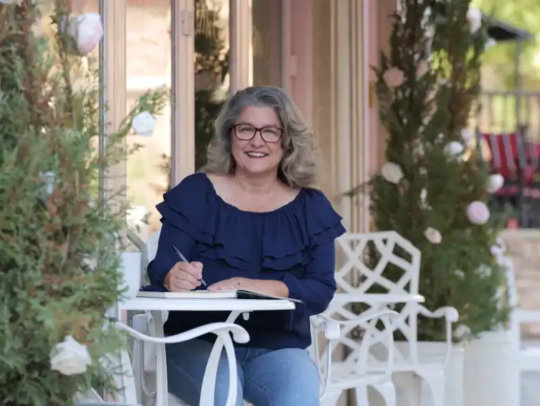 Linda Lutz, career coach, writing in journal on outdoor patio - designing a life she loves