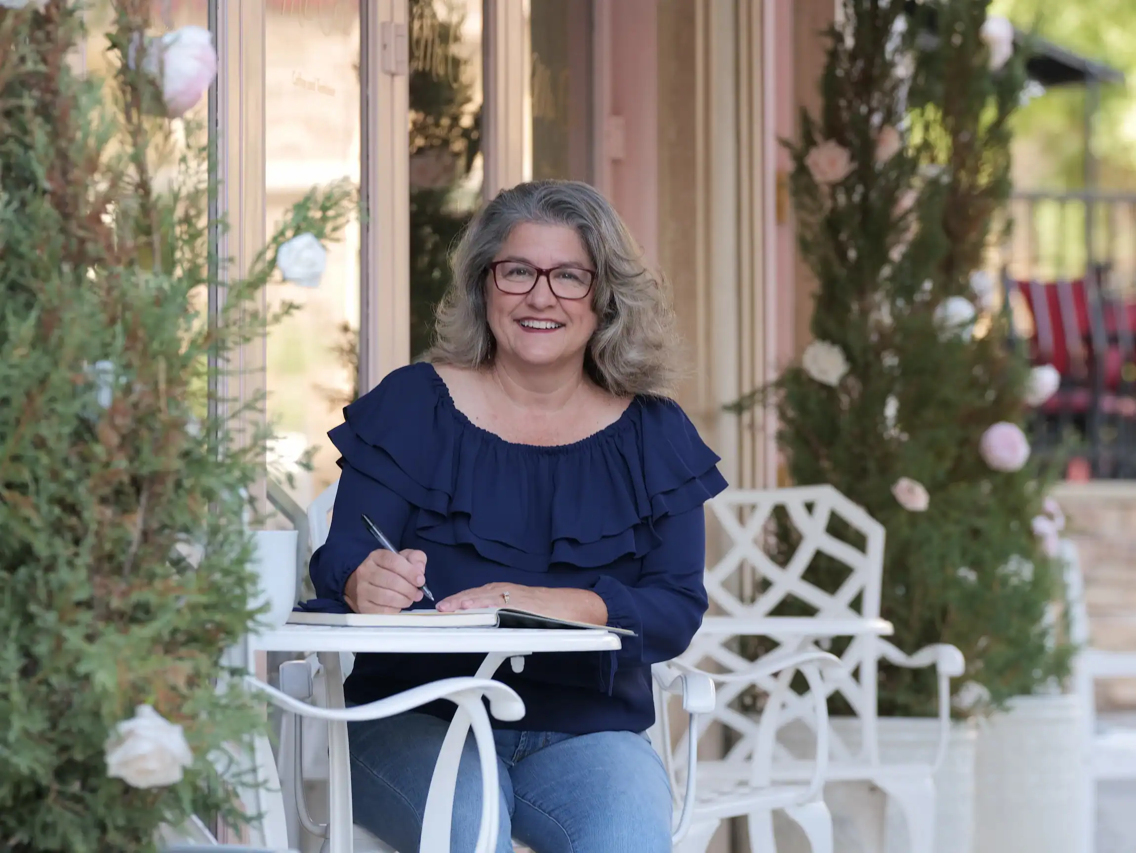 Linda Lutz, career coach, writing in journal on outdoor patio - designing a life she loves