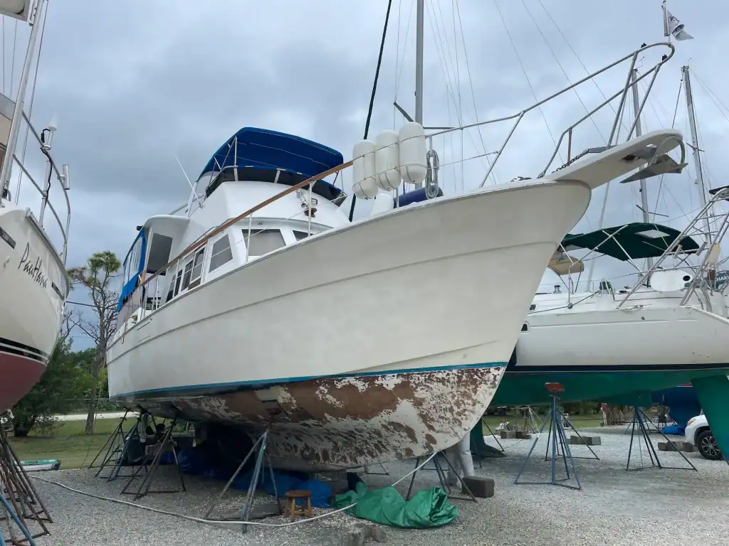 Motor yacht on stands with worn bottom paint before repairs