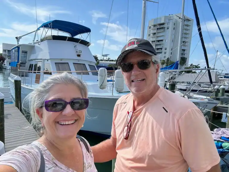 Matt and Linda smiling at the dock in front of their classic motor yacht Slow Ride on the day they sold her