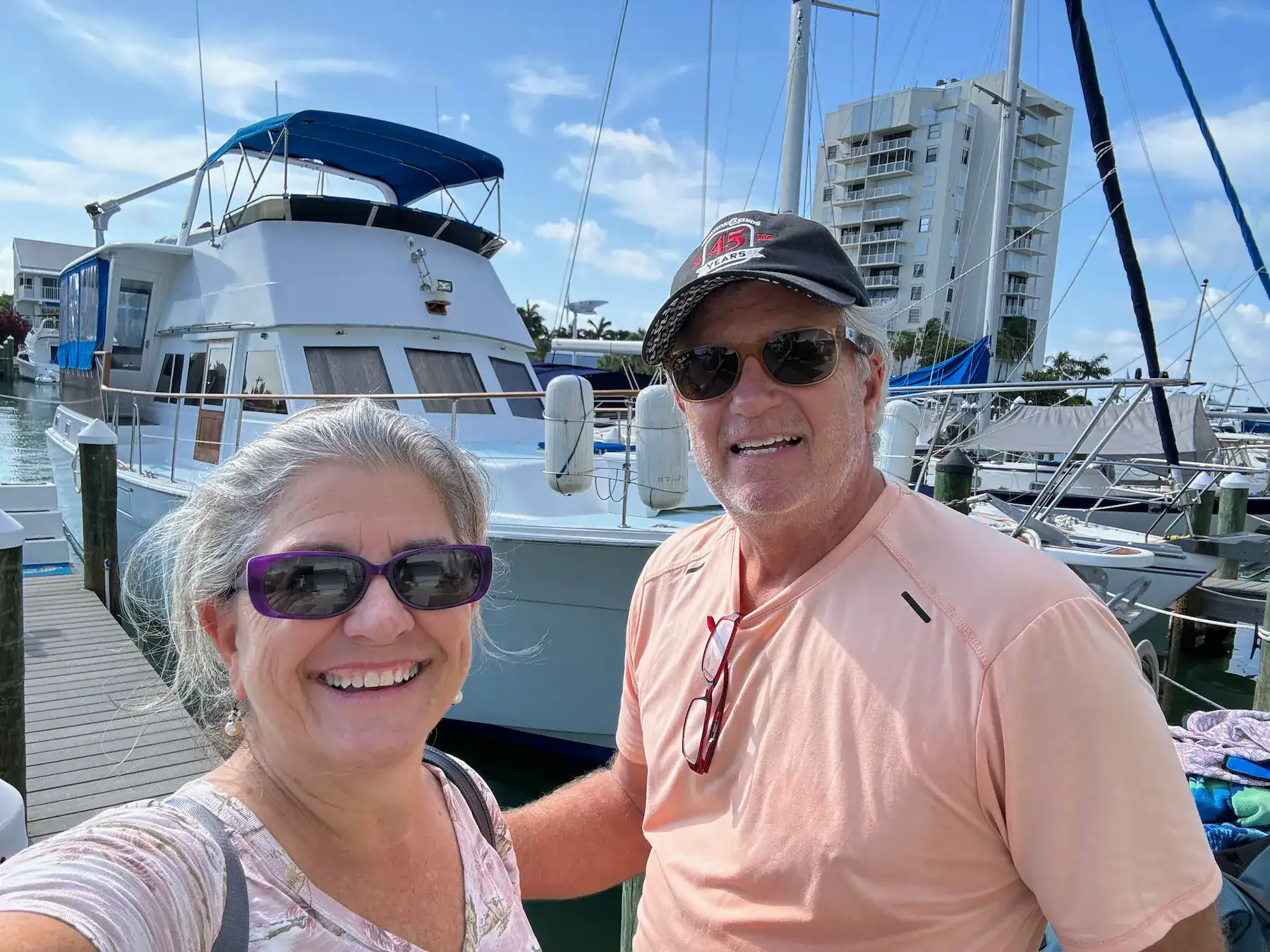 Matt and Linda smiling at the dock in front of their classic motor yacht Slow Ride on the day they sold her